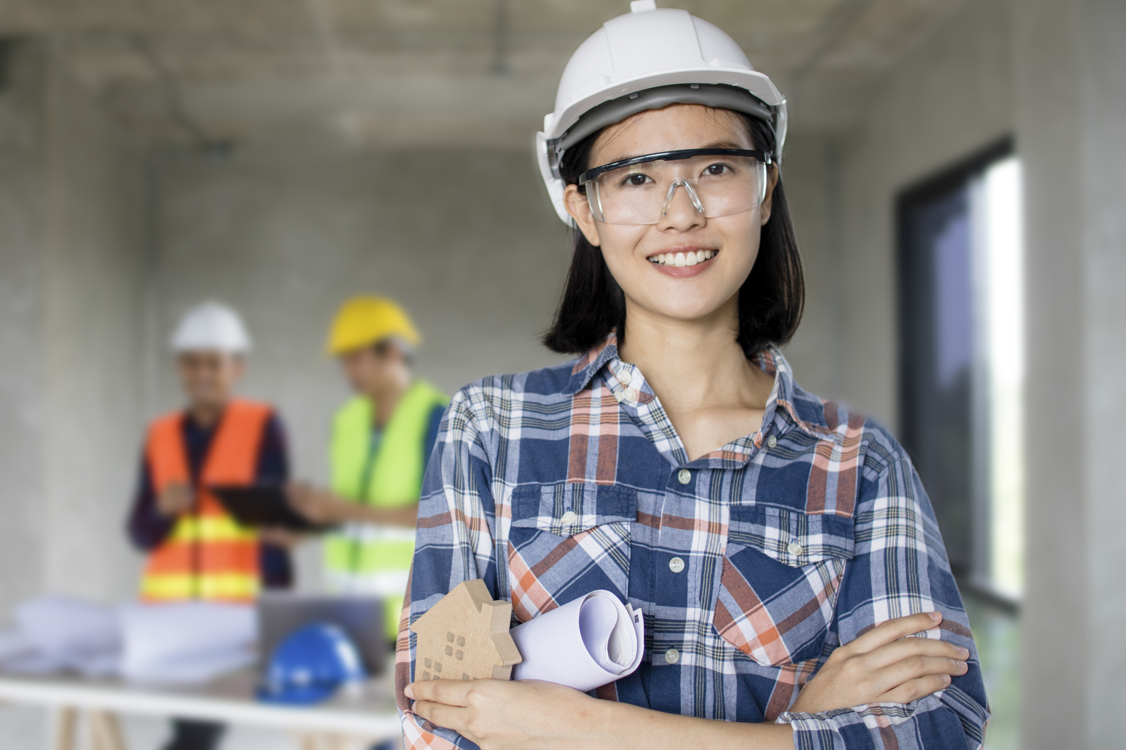 portrait of engineering women at construction site with worker working behind background portrait of engineering women at construction site with worker working behind background