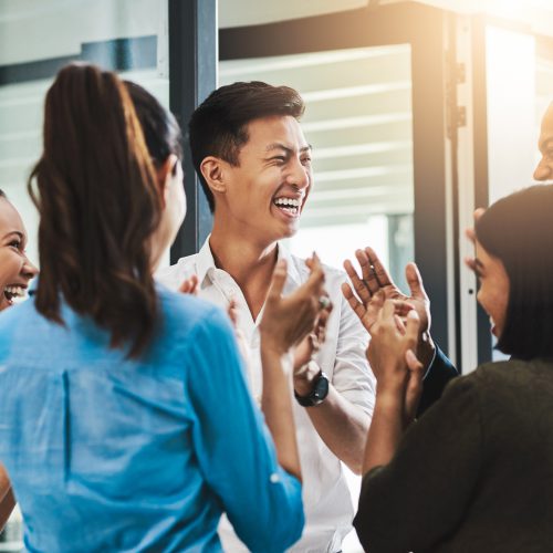 Shot of a group of young businesspeople standing together and clapping in a modern office