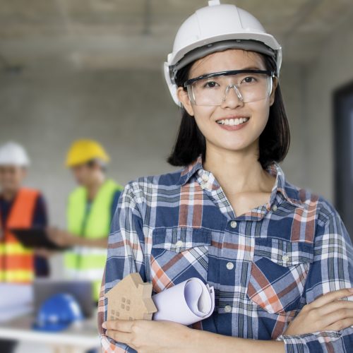 portrait of engineering women at construction site with worker working behind background